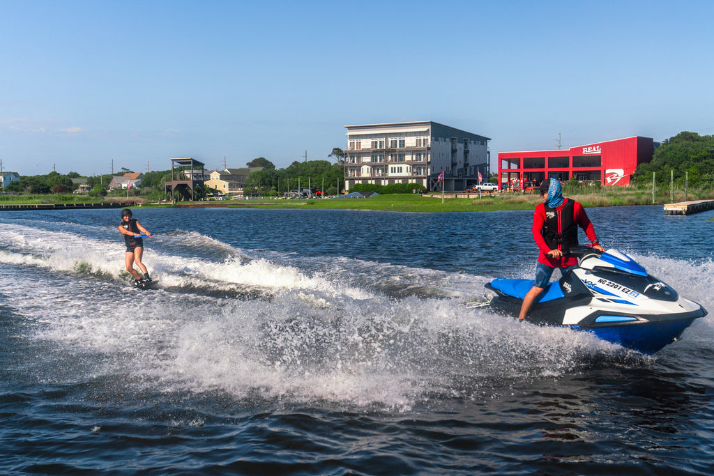 Kiteboarder practicing board skills behind a Jet Ski