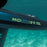 Close-up underwater shot of a black hydrofoil board with neon green branding reading 'MIDI PRO | 5'9 70L' and part of the 'NORD' brand name visible on the vertical stabilizer, set against turquoise ocean water.